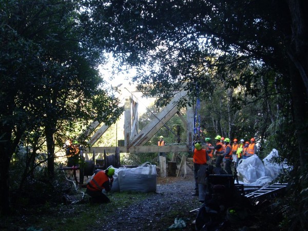 DOC staff carefully manouvere the headframe into place as contractors stand by to secure it onsite